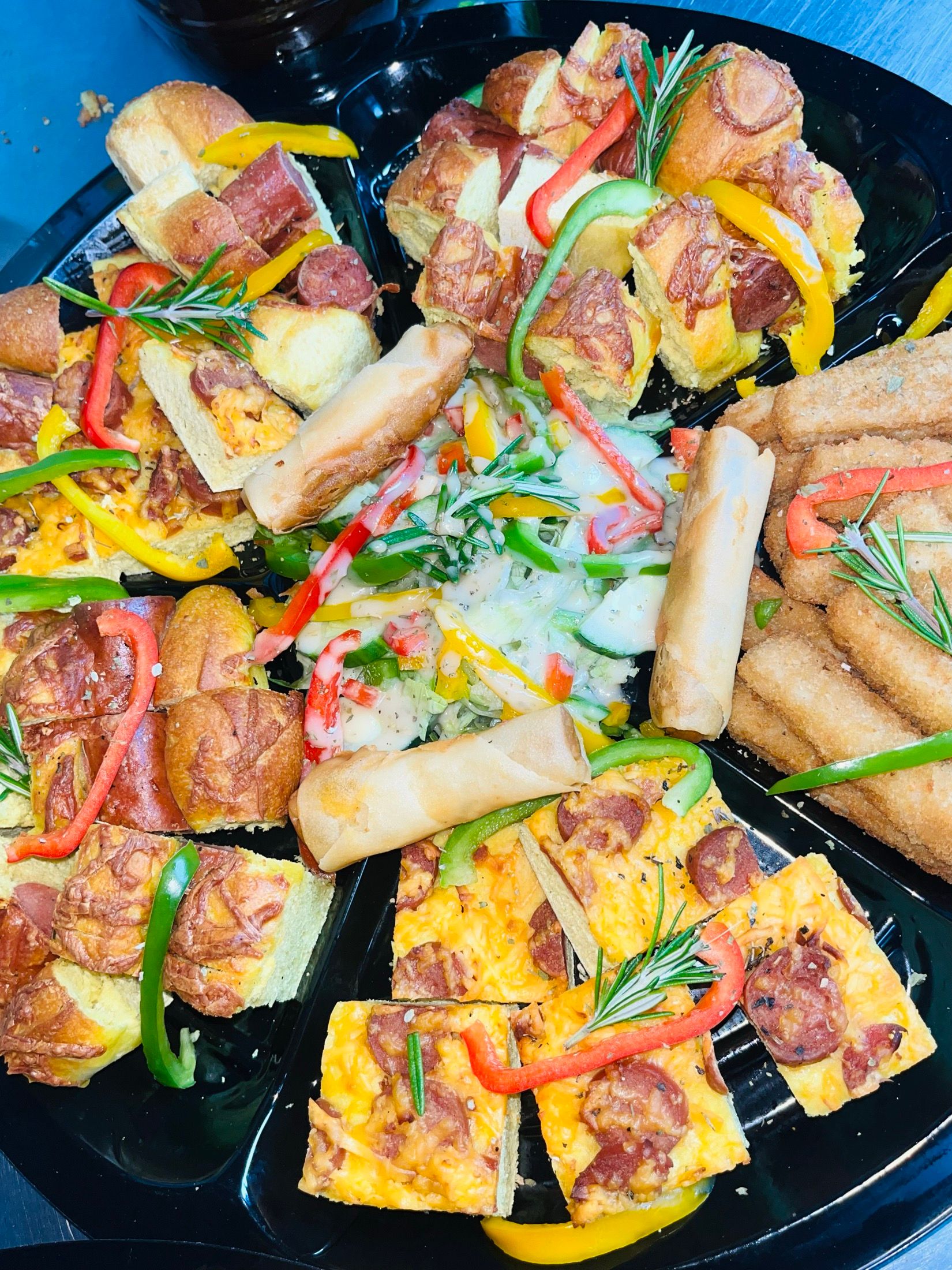A Black Diamond catering platter: spring rolls, frittata wedges and potato wedges around a bowl of creamy dip, scattered with pepper strips and rosemary.