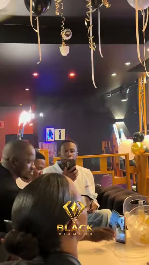 A VIP table at Black Diamond: bottles brought out with lit sparklers under a cluster of gold, black and white balloons, the party filming on their phones.